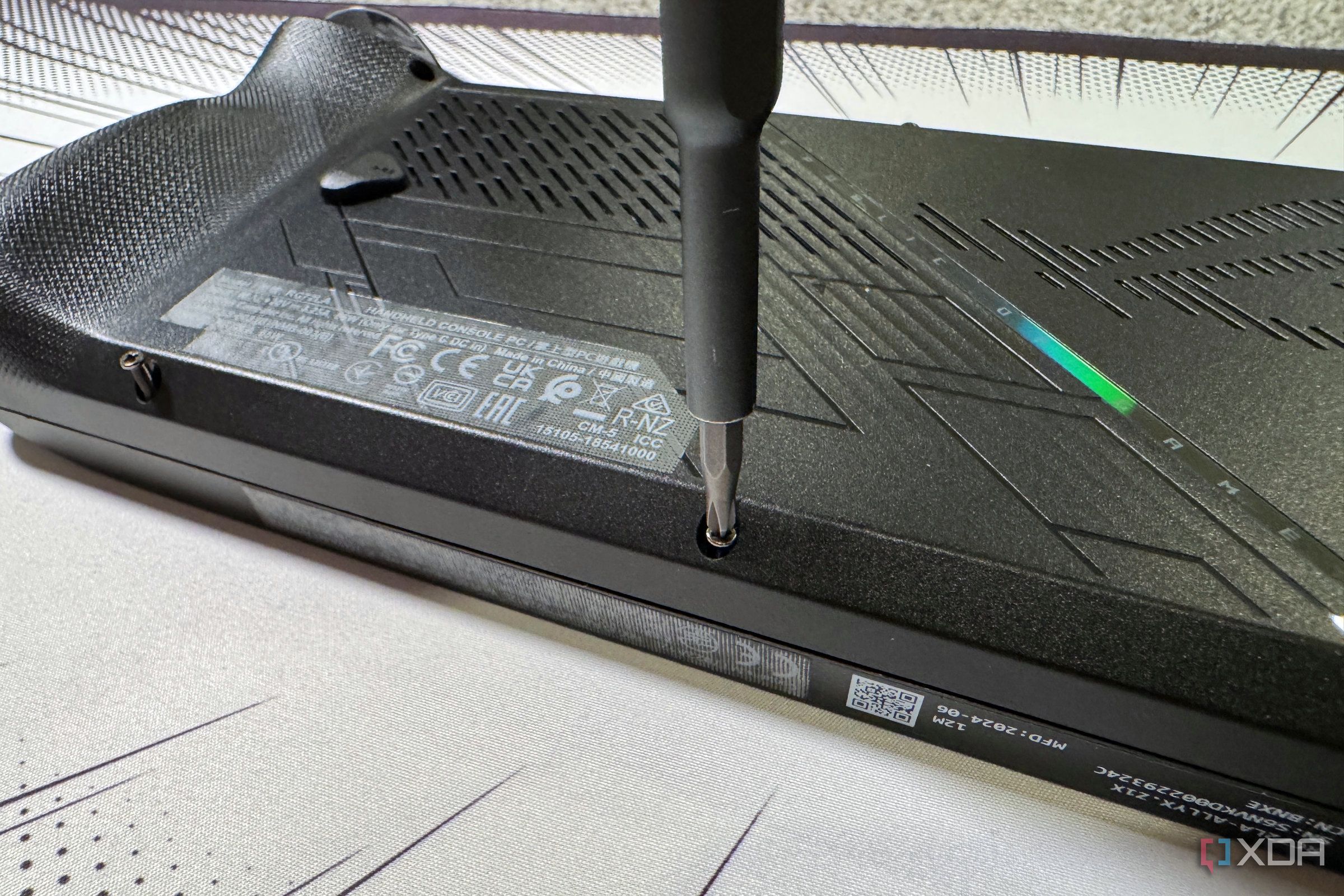 screwdriver refastening the rog ally x back panel