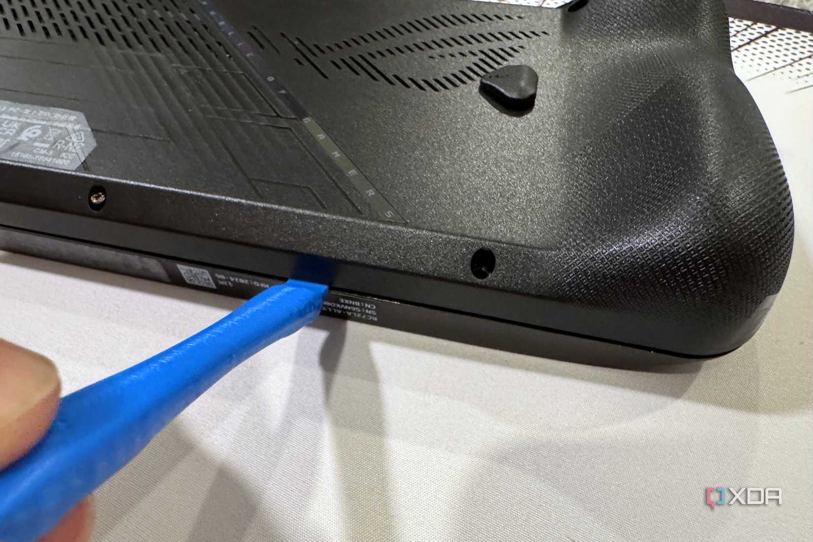rog ally x back panel being pried off with a plastic prybar