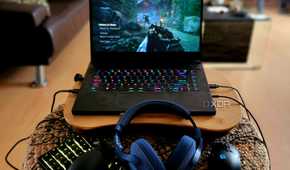 A gaming laptop on a lap desk with peripherals.