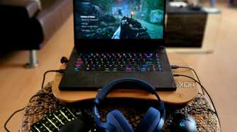 A gaming laptop on a lap desk with peripherals.