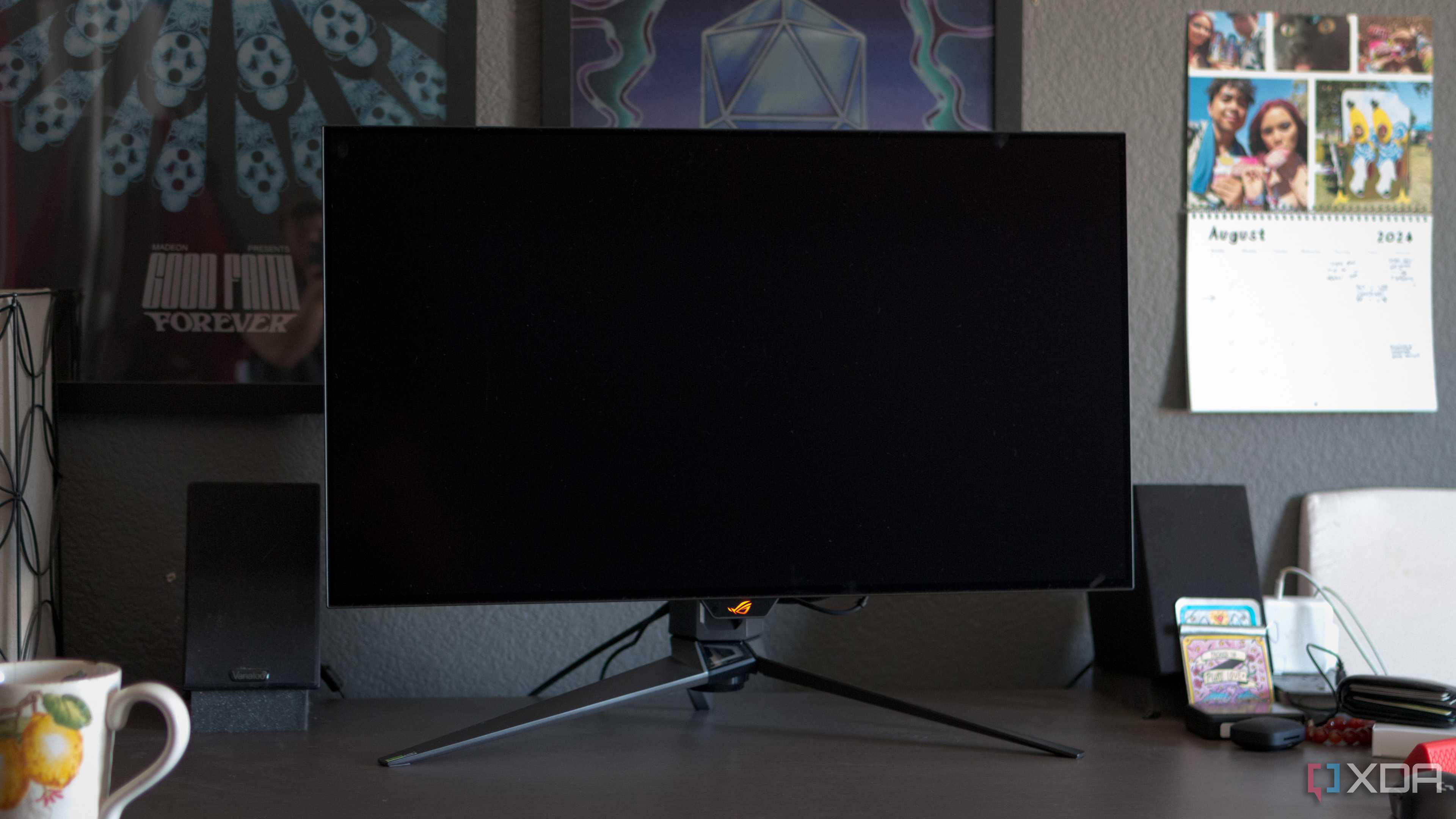 The ASUS ROG PG32UCDP showing a black screen on a desk.