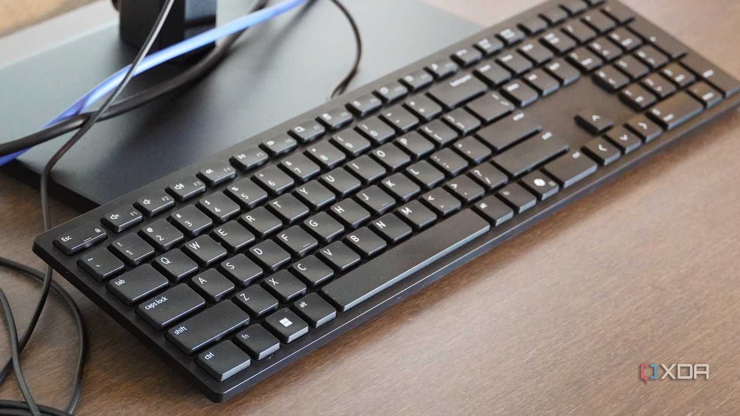 The Dell Wired Collaboration Keyboard on a monitor stand.