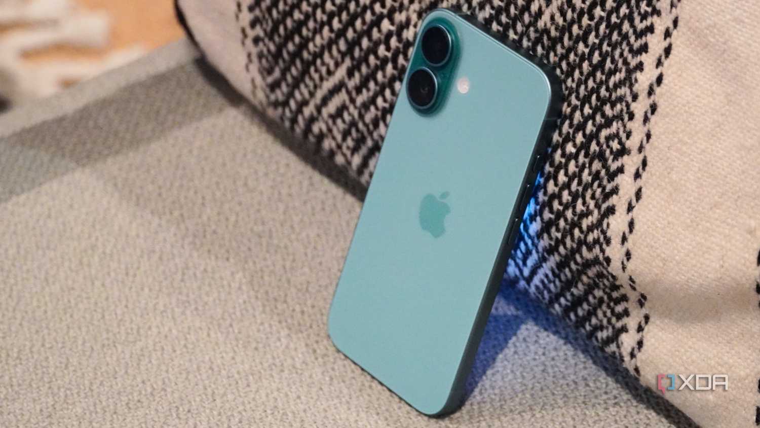 The iPhone 16 leaning against a pillow.