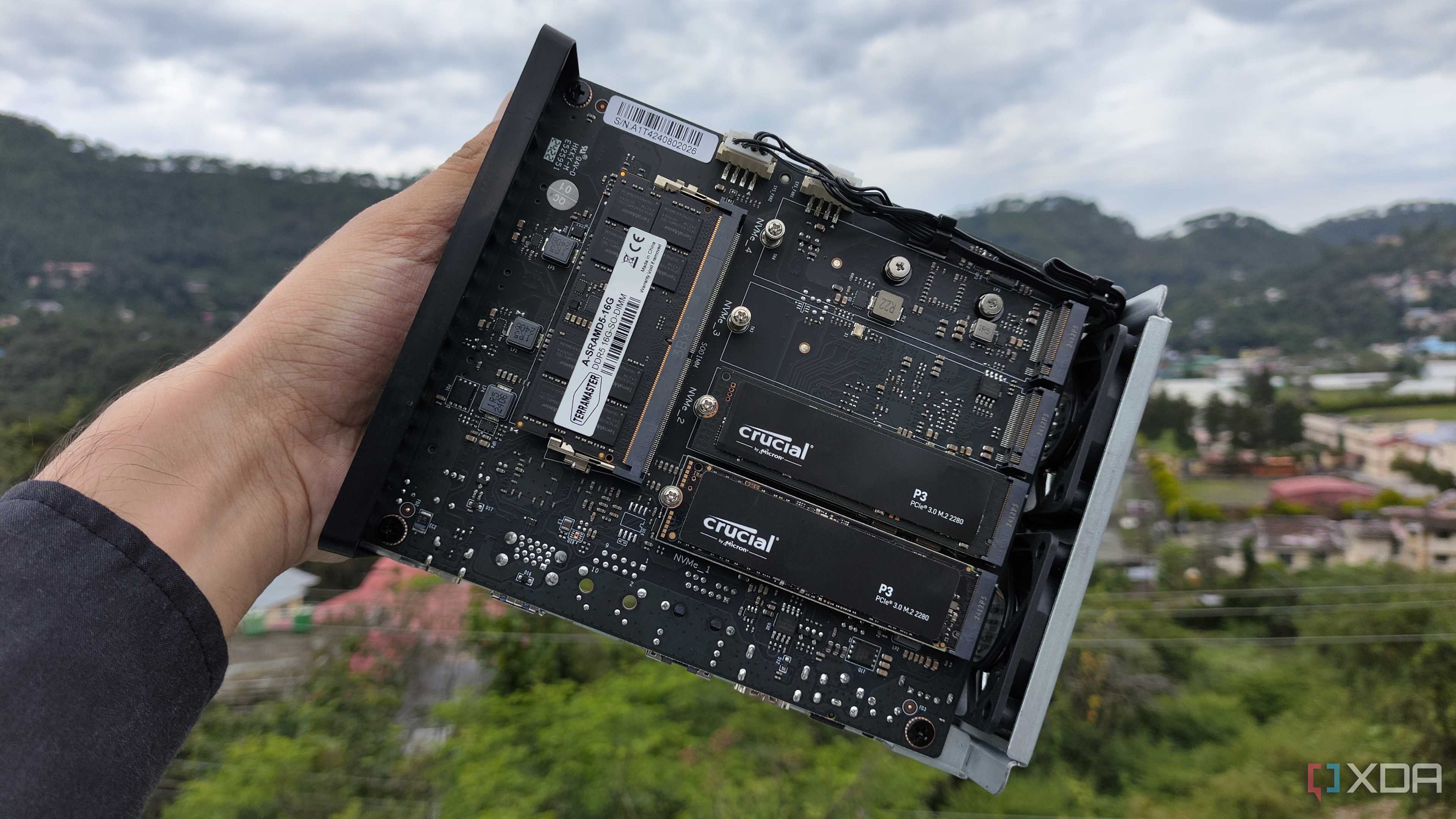 A person holding a TerraMaster F8 SSD Plus, with two PCIe 3 SSDs slotted into the NAS