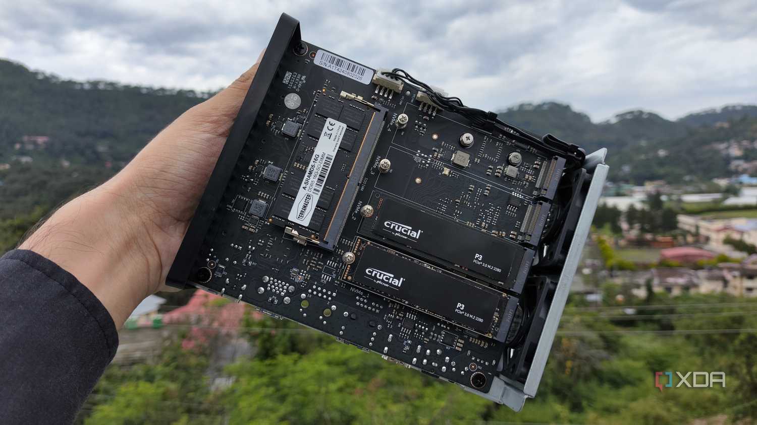 A person holding a TerraMaster F8 SSD Plus, with two PCIe 3 SSDs slotted into the NAS