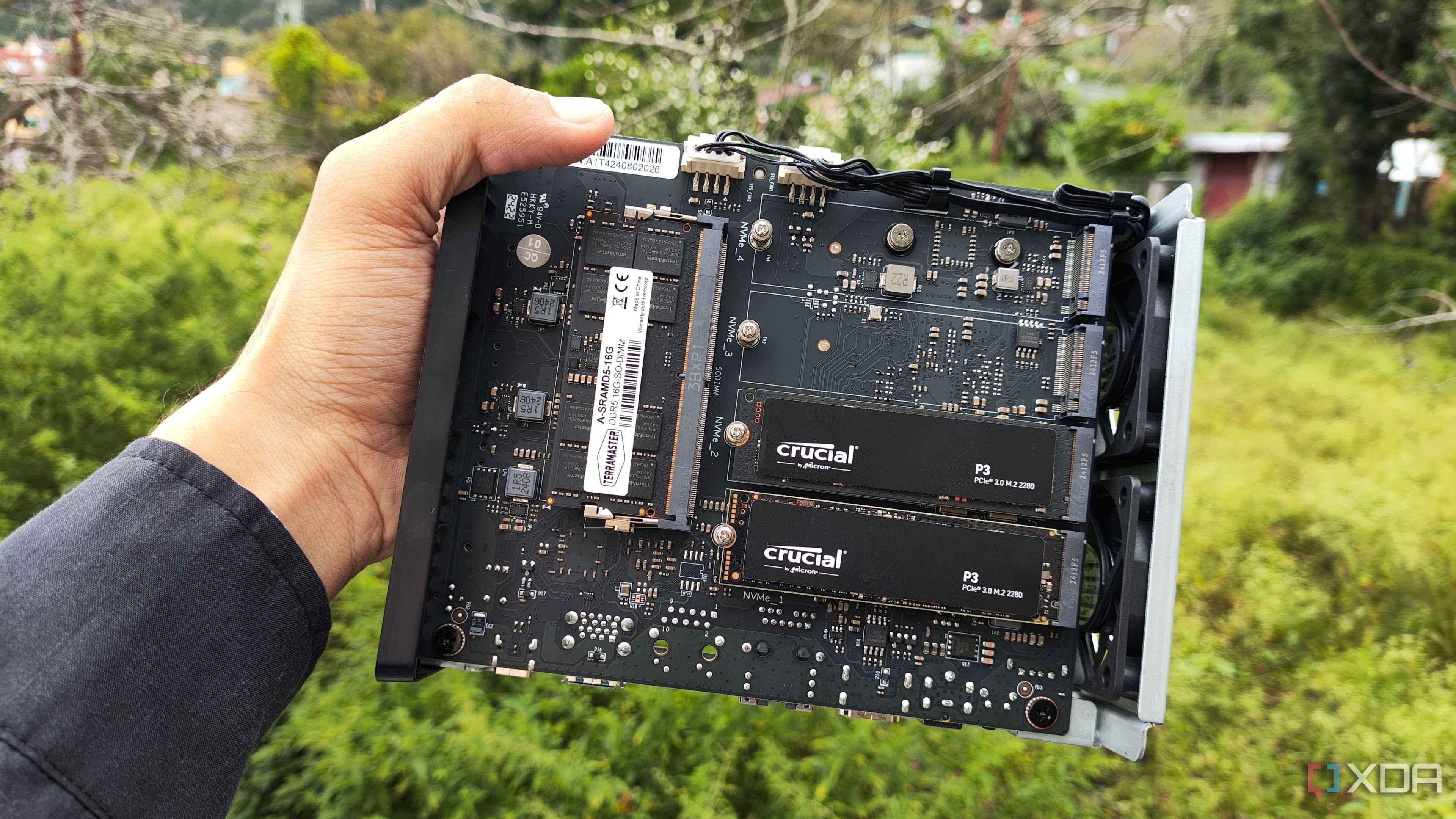 A person holding a TerraMaster F8 SSD Plus, with two PCIe 3 SSDs slotted into the NAS
