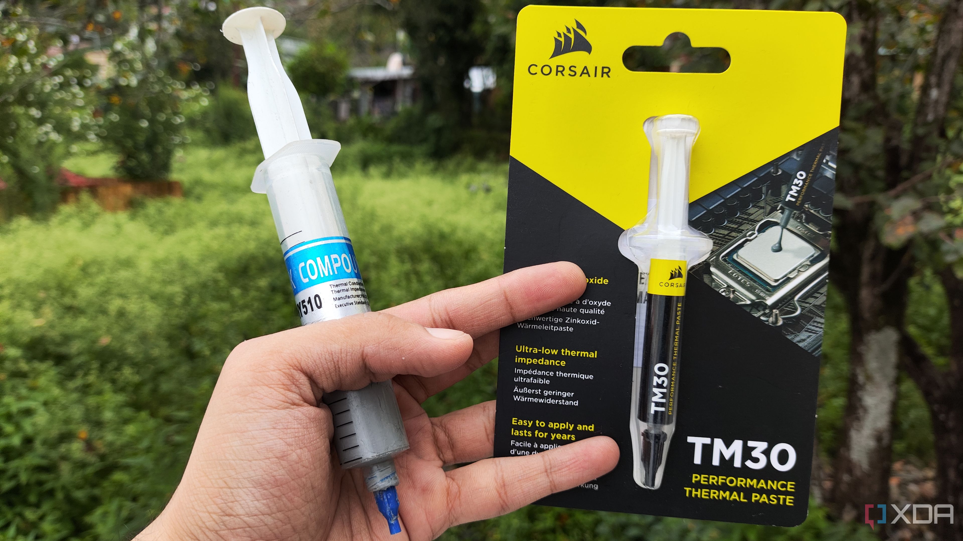 A person holding an Unbranded Thermal Paste and a Corsair TM30