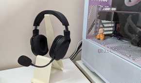 A gaming headset on a headphone stand next to a gaming PC on a white desk