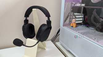 A gaming headset on a headphone stand next to a gaming PC on a white desk