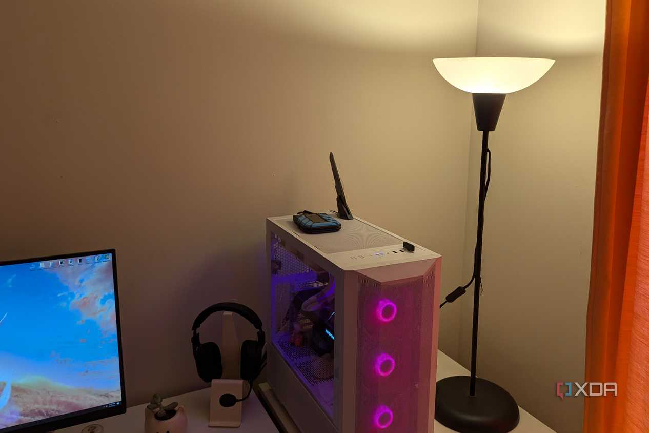 A warm lighting lamp next to a gaming PC and white desk