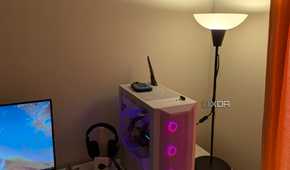 A warm lighting lamp next to a gaming PC and white desk