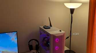 A warm lighting lamp next to a gaming PC and white desk
