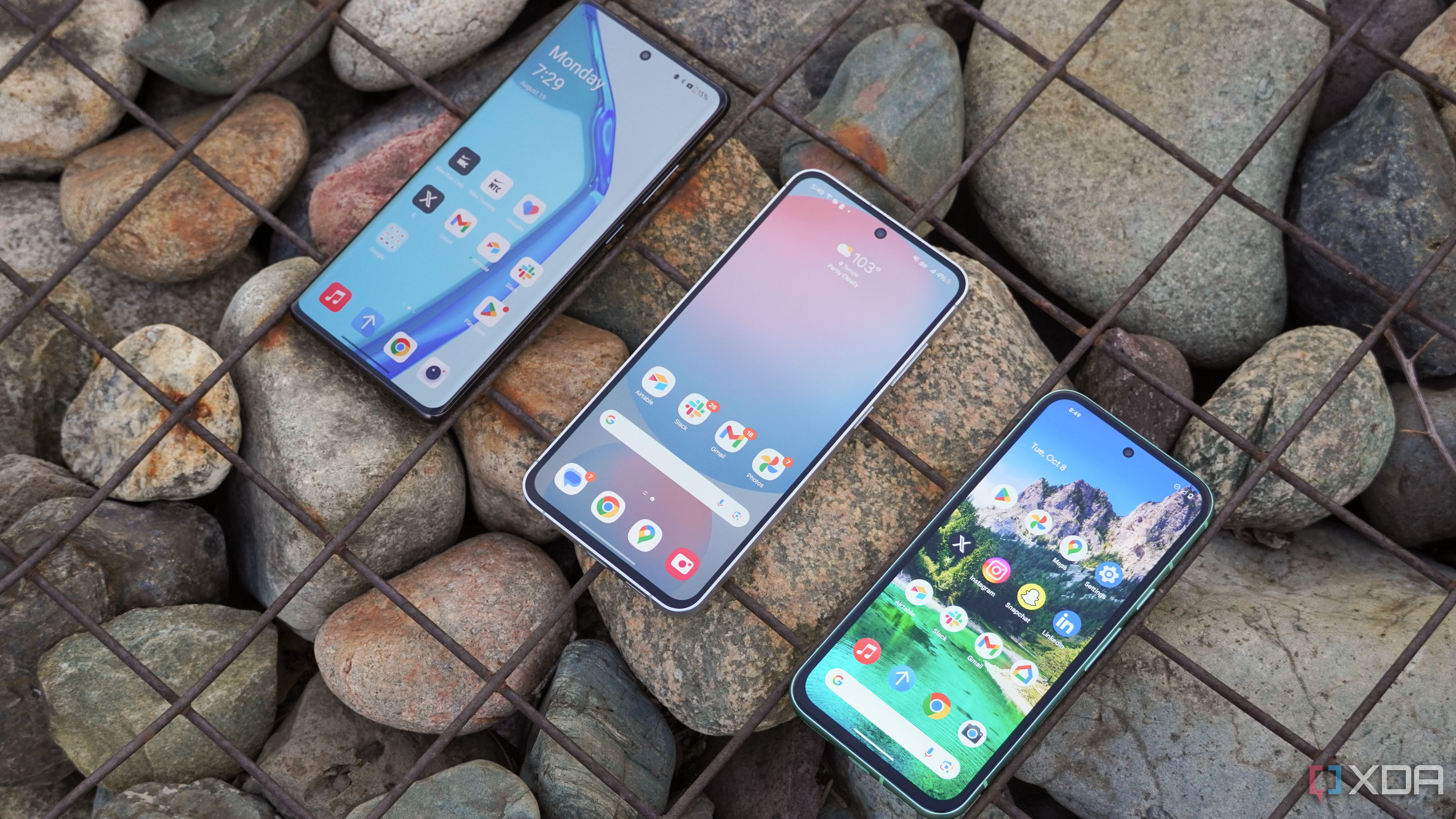 The Samsung Galaxy S24 FE, OnePlus 12R, and the Pixel 8a side by side with large stones in the background