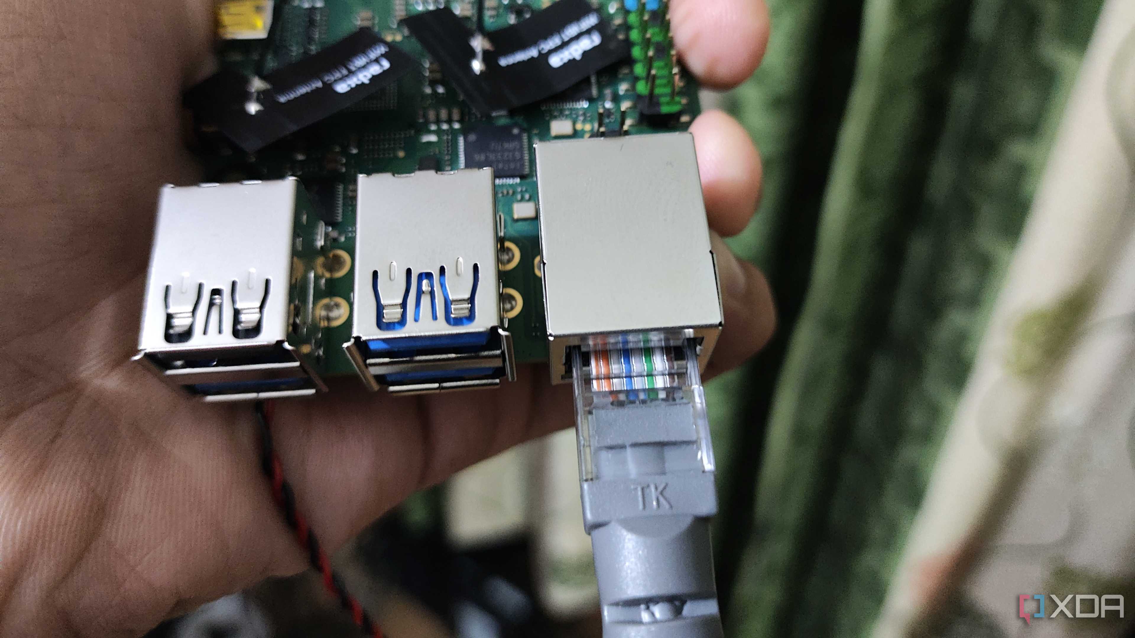 A person holding a Radxa X4, with an Ethernet cable plugged into the SBC