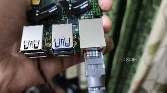 A person holding a Radxa X4, with an Ethernet cable plugged into the SBC