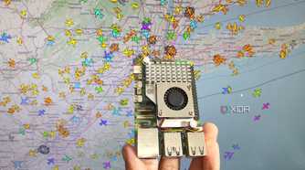 A person holding a Raspberry Pi 5 in front of an airplane tracking system