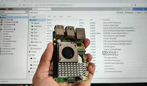 A person holding a Raspberry Pi in front of a PC