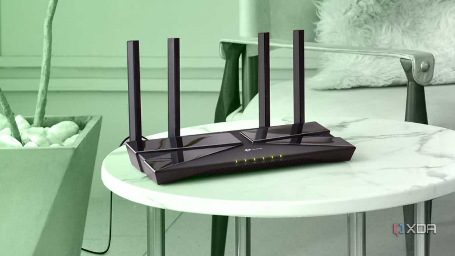 A black Wi-Fi router on a small round table with a green background