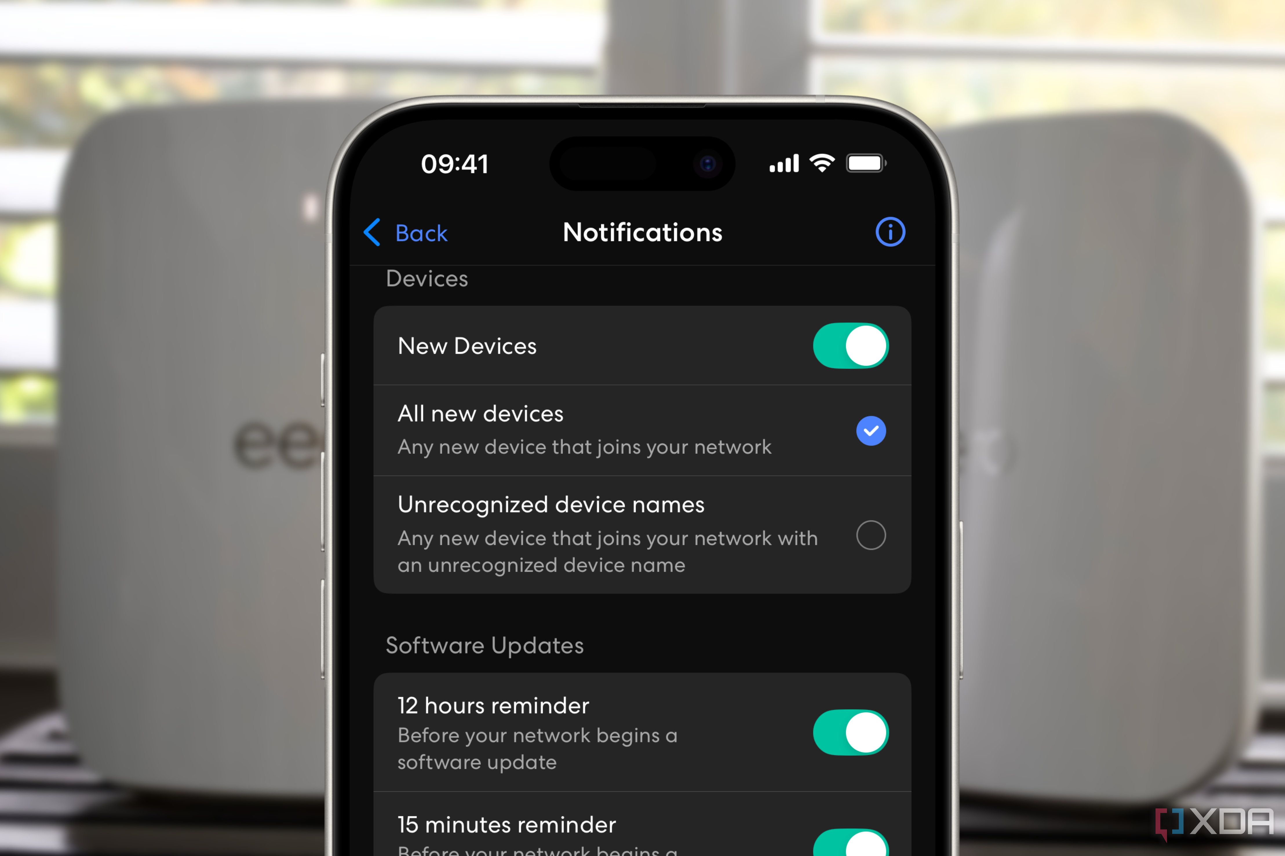 eero app showing new device notification setting over a blurred background of two white routers