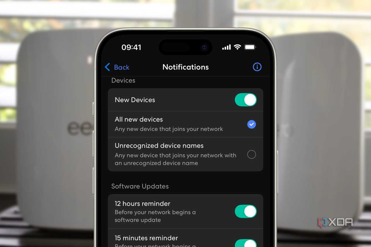 eero app showing new device notification setting over a blurred background of two white routers