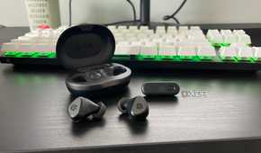 The SteelSeries Arctis GameBuds displayed outside their case in front of a mechanical gaming keyboard.