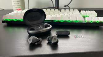 The SteelSeries Arctis GameBuds displayed outside their case in front of a mechanical gaming keyboard.