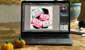 Krita vector on a MacBook laptop sat on a wooden table with knitted ornaments surrounding it
