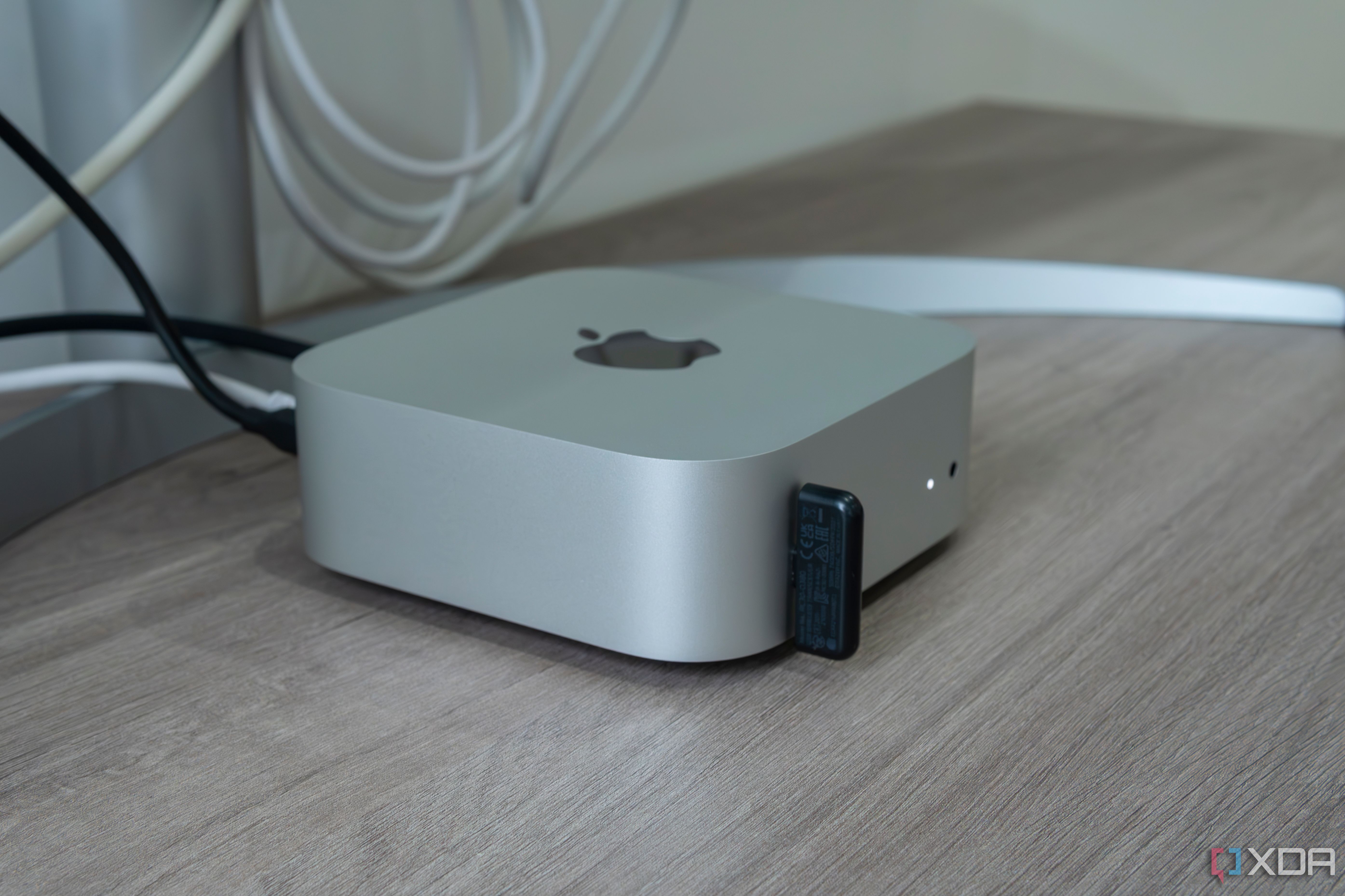 Side view of the M4 Mac Mini with a USB dongle plugged into one of the ports on the front