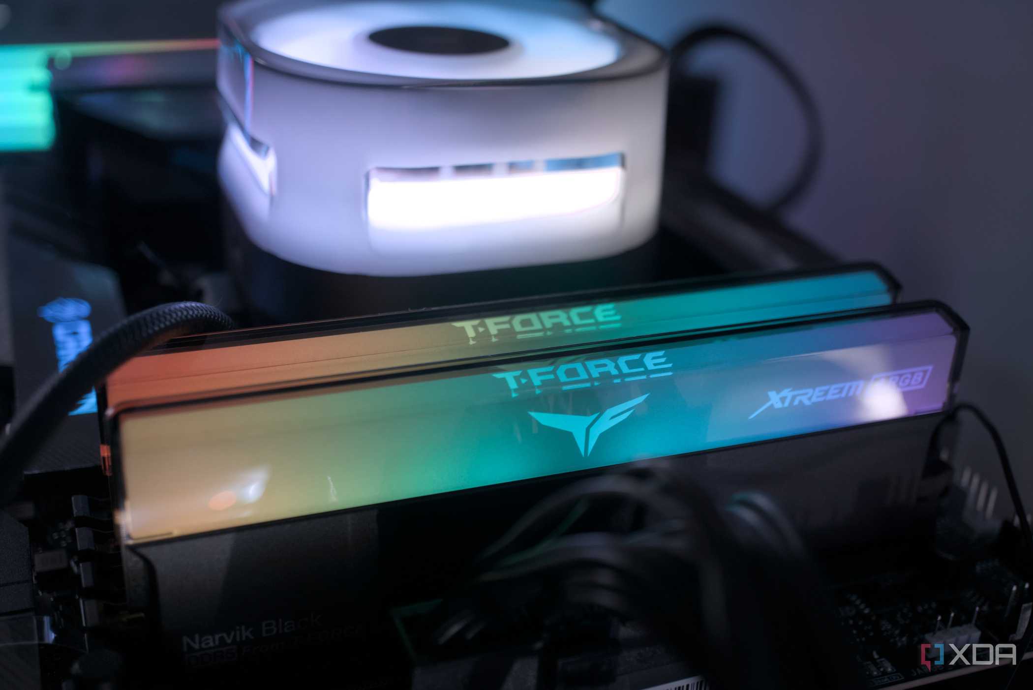 An image of RGB RAM modules installed on a motherboard across a CPU fan.