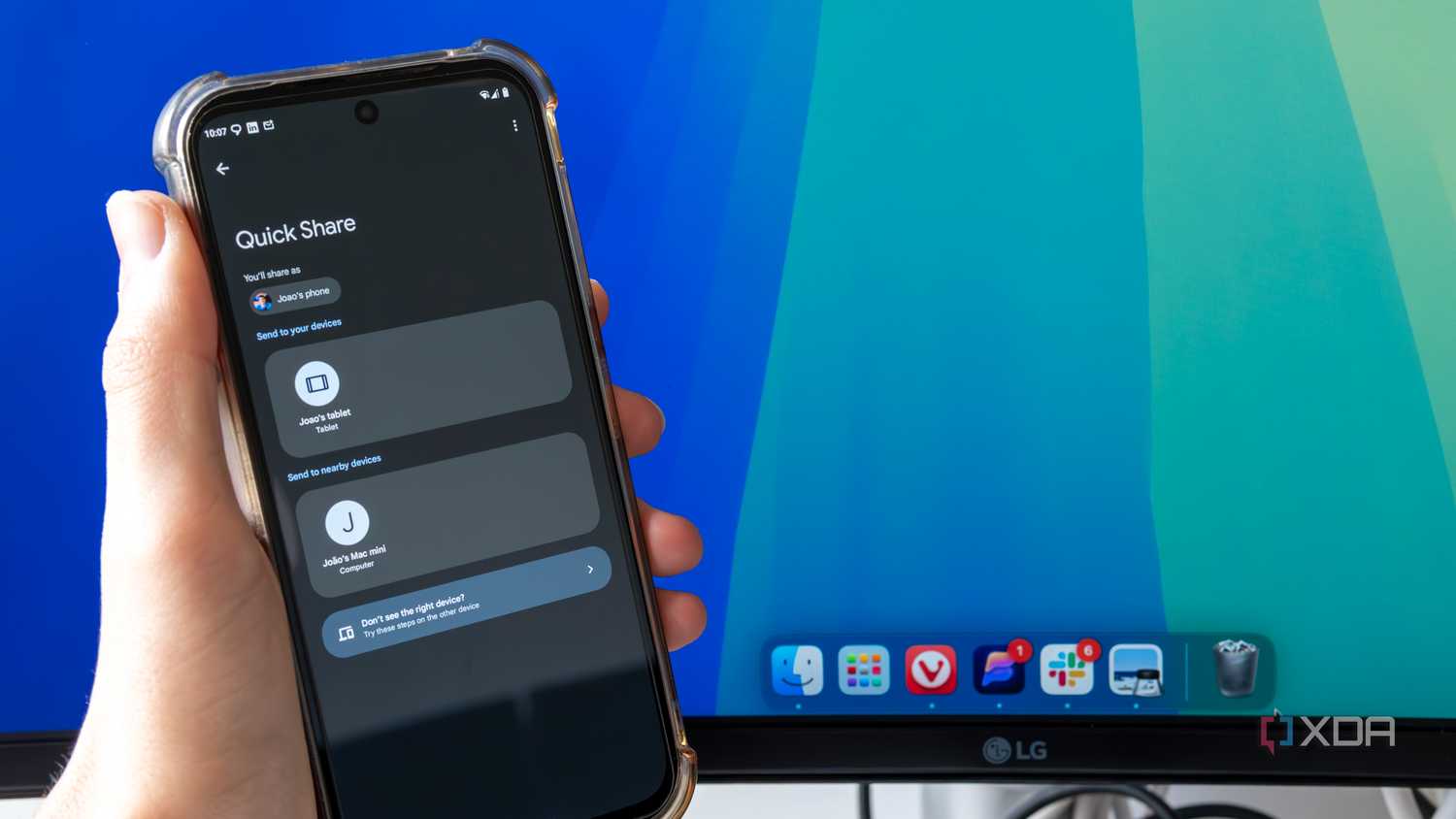 An Android phone trying to share a file using Quick Share with a Mac desktop in the background. The phone shows a Mac Mini as an available sharing target