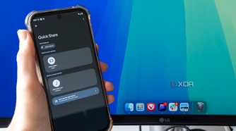 An Android phone trying to share a file using Quick Share with a Mac desktop in the background. The phone shows a Mac Mini as an available sharing target
