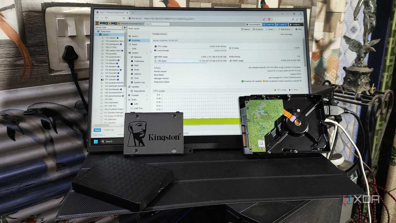 Some HDDs and a Kingston SSD placed in front of a monitor displaying the Proxmox web UI