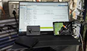 Some HDDs and a Kingston SSD placed in front of a monitor displaying the Proxmox web UI