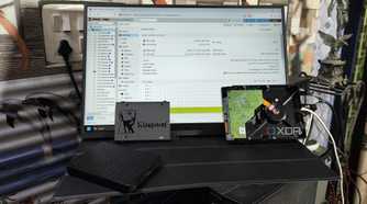 Some HDDs and a Kingston SSD placed in front of a monitor displaying the Proxmox web UI