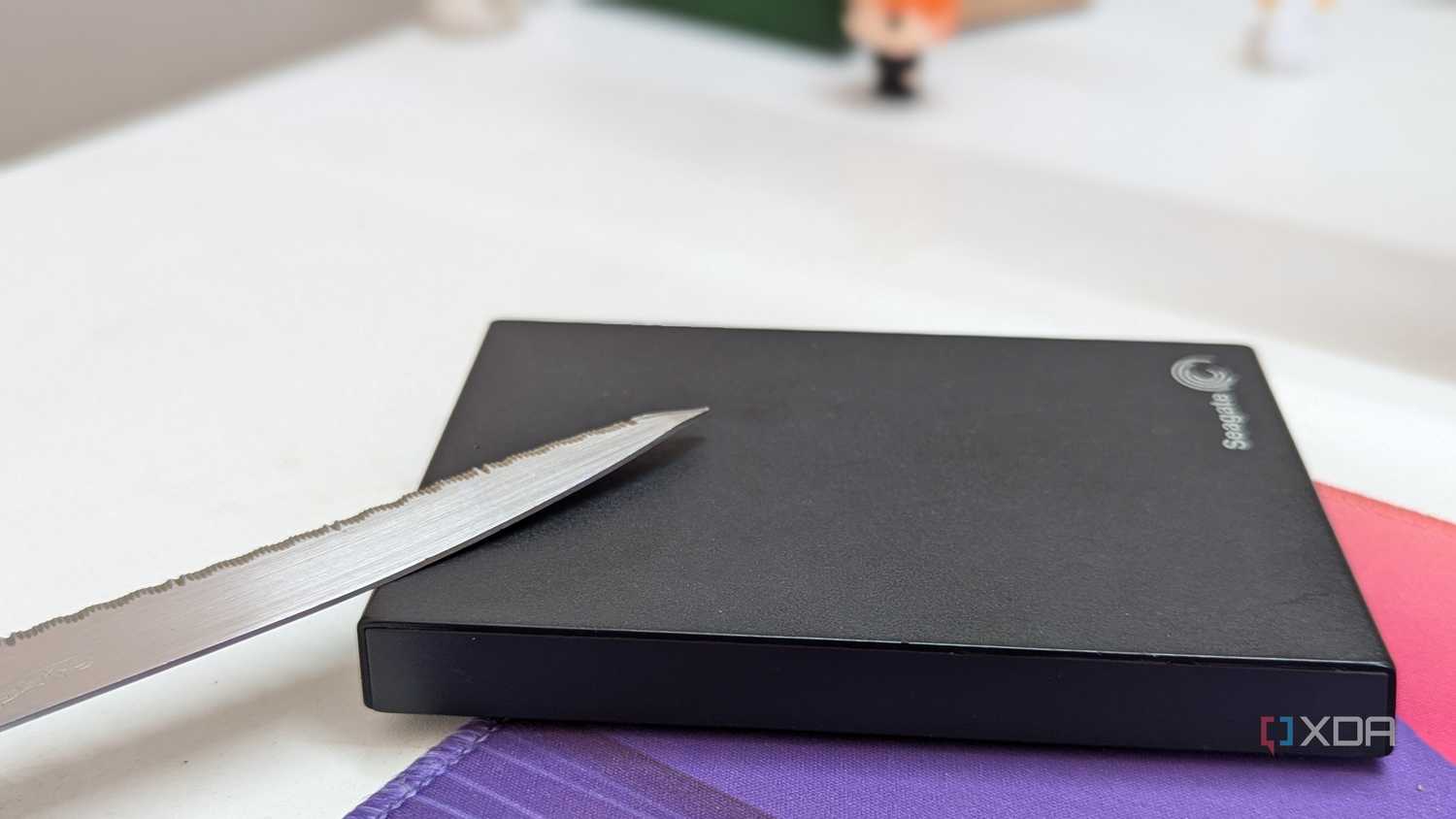 A black external hard drive with a metal blade on a desk