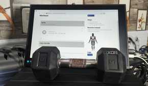 A dumbbell placed in front of a monitor displaying the wger UI