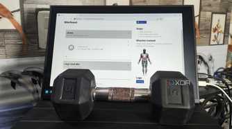 A dumbbell placed in front of a monitor displaying the wger UI