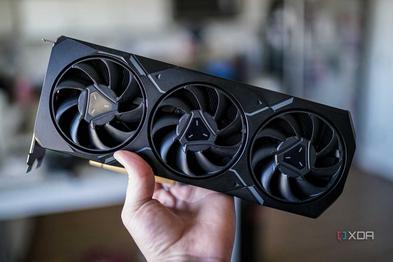 A hand holding AMD's RX 7900 XT graphics card.