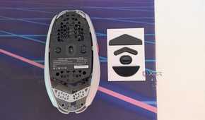 Bottom view of a gaming mouse next to mouse feet on a desk mat