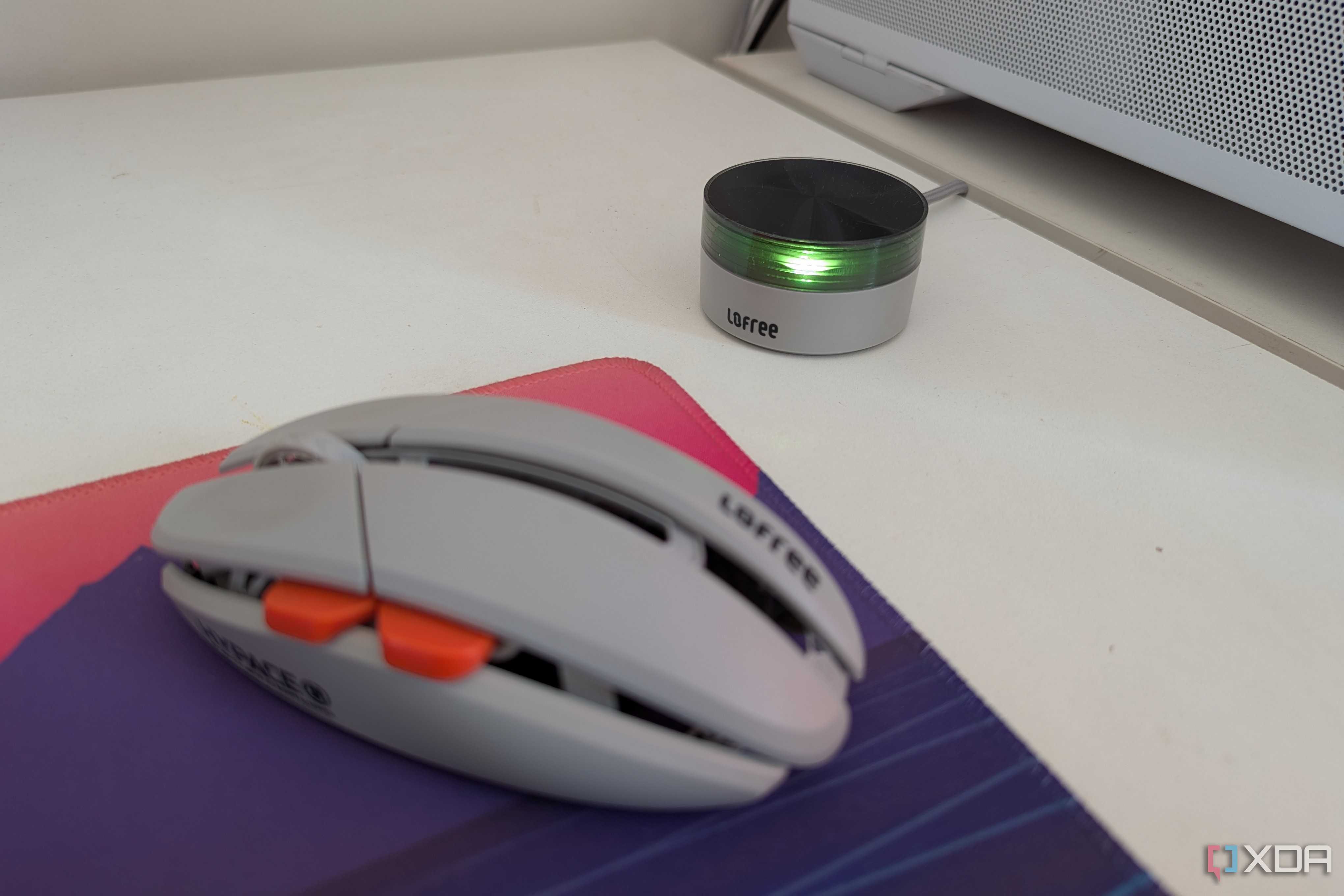 A gaming mouse next to its wireless dongle on a white desk