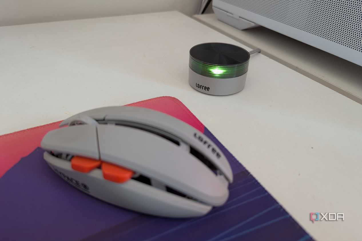 A gaming mouse next to its wireless dongle on a white desk