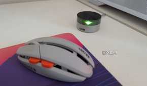 A gaming mouse next to its wireless dongle on a white desk