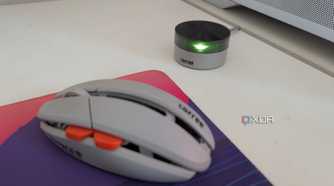 A gaming mouse next to its wireless dongle on a white desk