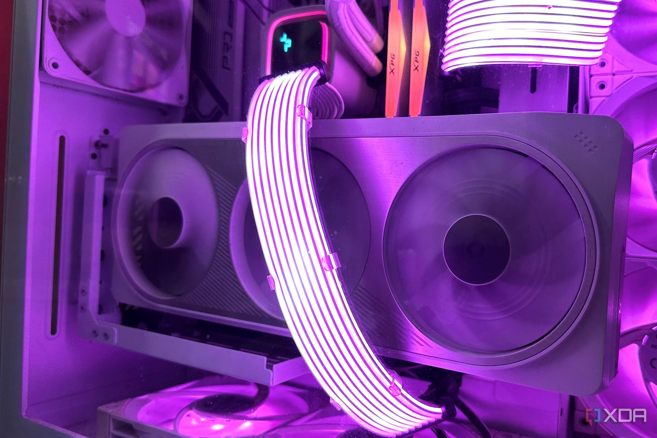 Una Nvidia RTX 4070 Ti blanca vertical dentro de un gabinete completamente blanco, con cables Lian Li Strimer iluminados en violeta atravesándolo.
