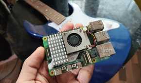 A person holding a Raspberry Pi 5 in front of a Yamaha Pacifica 012