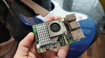 A person holding a Raspberry Pi 5 in front of a Yamaha Pacifica 012