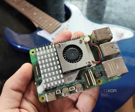 A person holding a Raspberry Pi 5 in front of a Yamaha Pacifica 012