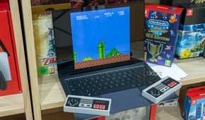 A Windows 11 laptop running Super Mario Bros in an emulator. Two wireless NES controllers are resting on it