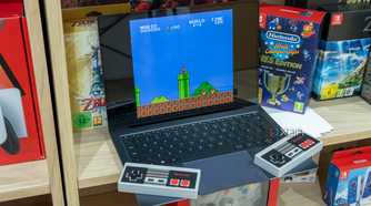 A Windows 11 laptop running Super Mario Bros in an emulator. Two wireless NES controllers are resting on it
