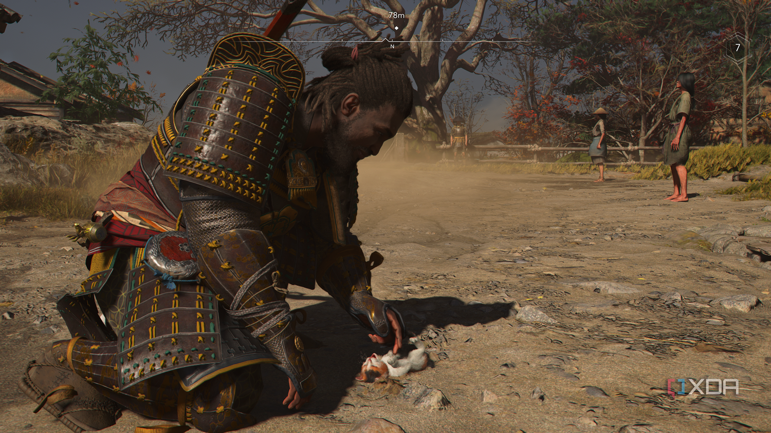 A screenshot from Assassin's Creed Shadows, showing Yasuke, the protagonist, playing with a kitten.